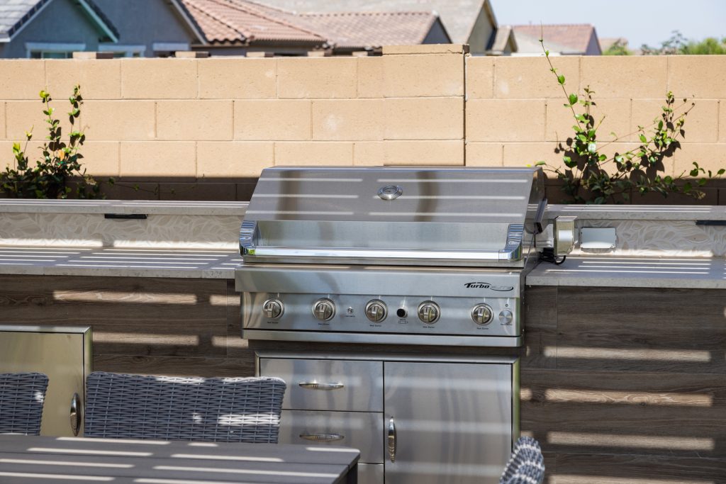 Custom outdoor bbq island with decorative tiled backsplash.