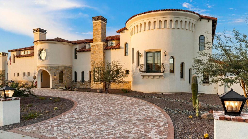Mediterranean-style home with desert landscape and curved driveway