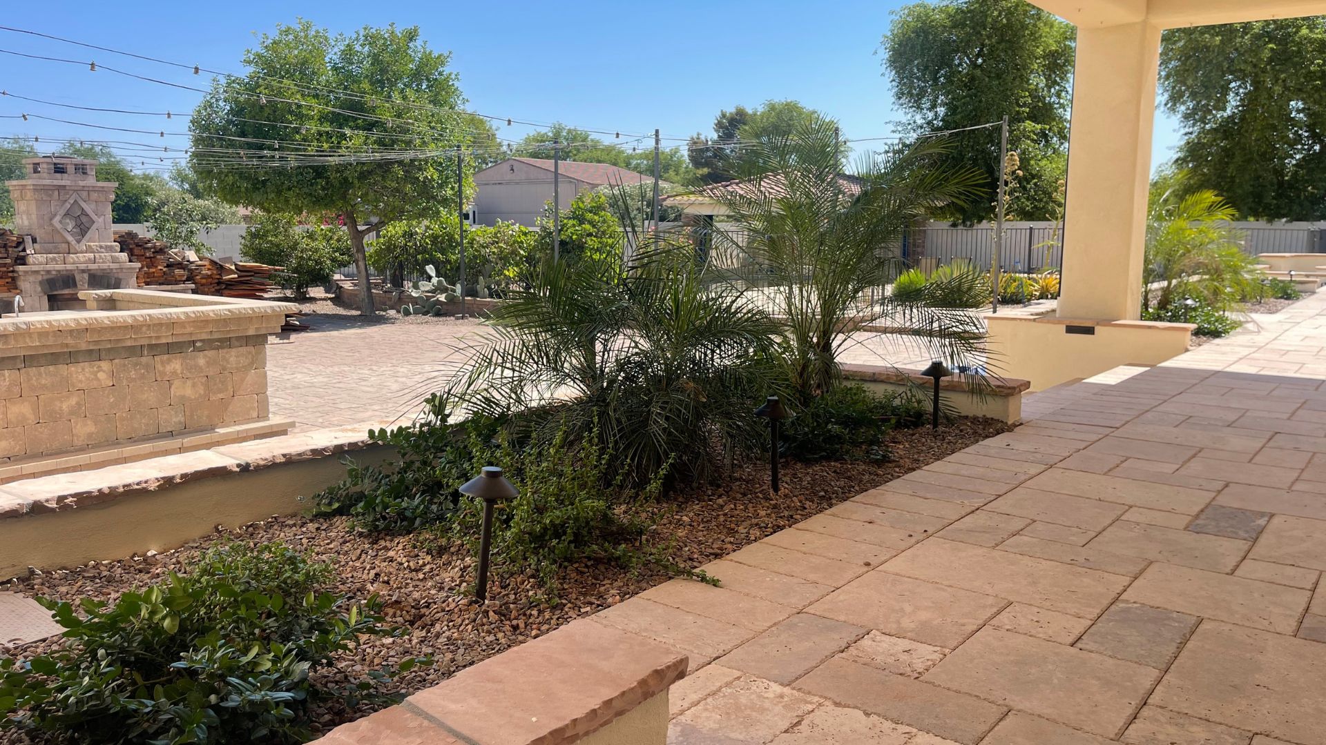 Spacious paver patio with desert plants and stone fireplace